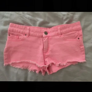 Rosa lågmidjade jeansshorts - Säljer ett par snygga rosa shorts med låg midja fransar i nederkant. De har en knapp och dragkedja framtill samt fickor både fram och bak. Säljer endast då de är för små! Midja: 38cm , längd 22cm. Ettiketten säger storlek 34, skulle säga Xs/s beroendd på