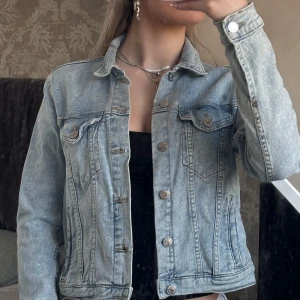 Ljusblå jeansjacka - Snygg ljusblå jeansjacka med knappar framtill och klassisk krage. Jackan har två bröstfickor med lock och knappdetaljer. Liten i storleken, sitter som xxs. 