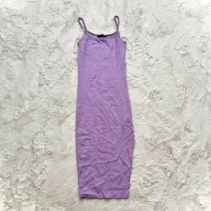 Ljuslila ärmlös klänning - Säljer en stilren ljuslila klänning med smala axelband. Klänningen har en enkel och elegant design som passar perfekt för varma dagar. Perfekt för att skapa en avslappnad och chic look.