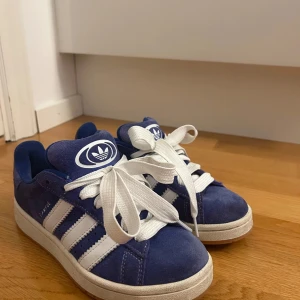 Adidas Campus Blå Sneakers - Säljer ett par blåa Adidas Campus sneakers i storlek 37 1/3. Skorna är i gott skick och har använts sparsamt. Perfekta för vardagligt bruk. Tyvärr har jag ej kvar skokartongen, men ser till att skicka varan säkert. Bara att skriva vid funderingar.💞
