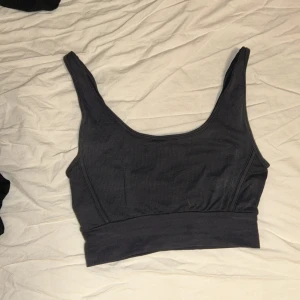 Svart ribbad linnetopp från Hummel - Säljer en svart ribbad linnetopp från Hummel. Toppen har en enkel design med breda axelband och en bekväm passform. Perfekt för träning eller en avslappnad dag.