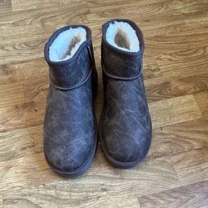 Bruna boots från Nelly - Säljer ett par mysiga bruna boots från Nelly med mjukt foder inuti. Perfekta för kyliga dagar med sin varma insida och stilrena design. De har en rund tå och är tillverkade i ett material som liknar mocka.