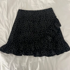 Svart prickig kjol med volang - En tajt svart prickig volang kjol med dragkedja baktill som passar perfekt nu till sommaren. Det finns ett litet hål baktill vid den nedre volangen, men inget man ser tydligt. Vet ej vart den kommer ifrån då den är köpt secondhand. Säg till om du har nån fundering💕