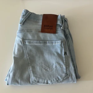 Ljusblå jeans från Replay  - Snygga ljusblå jeans från Replay Hyperflex med en klassisk femficksdesign. Modellen är Anbass De är tillverkade i ett stretchigt material för extra komfort och har en läderpatch med logotyp baktill. Perfekta för en avslappnad stil. Storlek 27/30