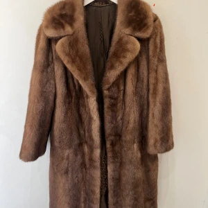 Brun pälsjacka från Saga - Elegant brun pälsjacka från Saga, tillverkad av mink från Skandinavien. Jackan har en klassisk design med långa ärmar och en mjuk, lyxig känsla. Perfekt för att hålla sig varm och stilfull under de kallare månaderna.