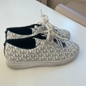 Sneakers från Michael Kors - Snygga sneakers från Michael Kors med ett grått och vitt mönster. Endast använda några gånger.  Storlek 38,5. Dessa skor är perfekta inför våren/sommaren. 