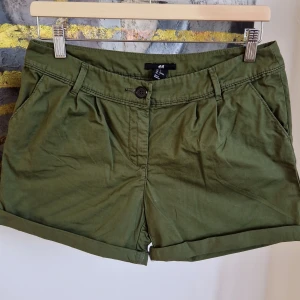 Gröna shorts från H&M - Snygga gröna shorts från H&M med knapp och dragkedja framtill. De har en klassisk design med fickor både fram och bak. Perfekta för en avslappnad stil under varma dagar. 🌿 35cm
