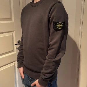 Stone island tröja - Säljer en stilren mörkgrå sweatshirt från Stone Island med deras ikoniska märke på ärmen.  Säljer för att den inte används. Köpt på NK i Göteborg 