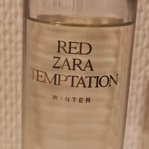 Red Zara Temptation Winter Parfym - Elegant parfymflaska från Zara med doften Red Temptation Winter. Flaskan är genomskinlig med en gyllene kork och text i guld. Perfekt för den som söker en sofistikerad och vinterinspirerad doft. 80 ml. Inte mycket använd, se bild 