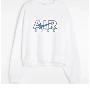 Vit sweatshirt från Nike - Säljer en vit sweatshirt från Nike med blått och svart tryck på framsidan. Tröjan har långa ärmar och en klassisk rund halsringning. Perfekt för en avslappnad stil.