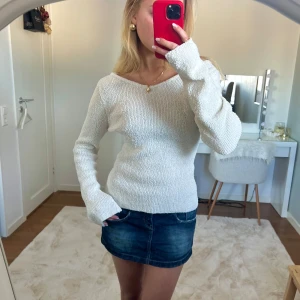 Vit stickad tröja - Säljer denna stilrena vit stickad tröja med lång ärm med slits och en v-ringad/halv-off-shoulder hals. Tröjan har en mjuk och bekväm passform. Den är i storlek m och slutsåld på h&m (säljs ej längre)