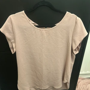 Beige blus från ONLY - Säljer en stilren beige blus från ONLY. Blusen har korta ärmar och en dragkedja i ryggen för en enkel och elegant look. Perfekt för både vardag och lite finare tillfällen.