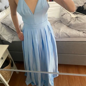 Ljusblå långklänning med djup urringning - Ljusblå långklänning med djup v-ringad urringning och korsade axelband i ryggen. Storlek 36, pris kan diskuteras!