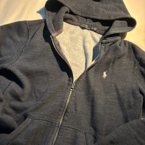 Polo Ralph Lauren Zip-Tröja - Fullzip från ralph lauren. Bra passform och en snygg, vintage look. Marinblå färg. Skick 8/10. Inga hål eller andra tydliga defekter. Strl M/M