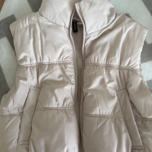 Ljusbeige dunväst från H&M - H&M väst, storlek S Har några fläckar på sig som inte går bort (se bild)