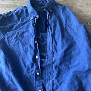 Blå skjorta från Ralph Lauren - Säljer denna blåa skjortan från Ralph Lauren! Skick 9/10, behövs bara strykas. M Custom fit.