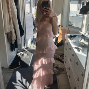 Ljusrosa lång volangklänning - Säljer vidare en rosa klänning med volanger från bohoo, lånade bilder och kan fixa egna. Endast använd en gång på min bal och säljer för att den har använts till det jag tänkte ha den till 💕