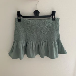 Volangkjol - Grön volangkjol från NA-KD.  Storlek XXS. Väldigt stretchig, passar därför XXS-S.  Midjan går att vika upp/ner så mycket som man själv önskar.