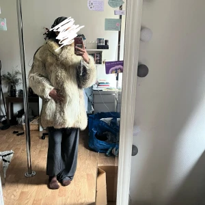Beige fejk pälsjacka med krage - Säljer en fluffig och väldigt varm beige fejk pälsjacka med bred krage. Jackan har lång ärm och stängs framtill. Finns ett hål vid insidan men som inte alls syns när man har den på!
