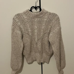 Beige stickad tröja från Object - Säljer en beige stickad tröja från Object i storlek XS. Tröjan har ett snyggt stickat mönster, ribbade muddar och hög hals. Perfekt för kyliga dagar och superenkel att styla till olika outfits.
