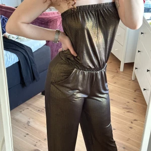 Glittrig jumpsuit  - Selling a glittery dark brown jumpsuit from Charlotte Russe with elastic at the top and waist. Wide legs and pockets on the sides. Perfect for those who want to stand out with a stylish and comfortable look for the summer. It is quite stretchy so it can fit from size S-M!