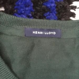 Grön tröja från Henri Lloyd - Mörkgrön tröja från Henri Lloyd med rund halsringning. Enkel och stilren design, perfekt för en avslappnad look. Tröjan har långa ärmar och är tillverkad i ett mjukt material.