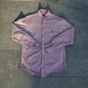 Ralph lauren skjorta - 📊 Färg: Vit, Marinblå och Orange  📏 Storlek: Medium (M)  📐 Mått: Längd - 76cm Axelbredd - 44cm  ♻️ En långärmad vit, orange och marinblå Ralph lauren skjorta i storlek M. I väldigt bra skick, inga fläckar, hål eller defekter! Perfekt nu när det börjar bli varmare och sommaren kommer!☺️  👕 Material: 100% Bomull  #mensfashion #mensstyle #ralphlauren #classicstyle #buttondown #shirt #fashion #Vintage #Ralphlaurenskjorta