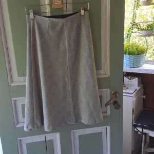 Ljusgrå långkjol i ullmix - Säljer en ljusgrå långkjol med klassisk A-linjeform. Kjolen har en enkel och stilren design utan synliga detaljer och är tillverkad i ett mjukt ullmaterial. Perfekt för dig som gillar en tidlös look.