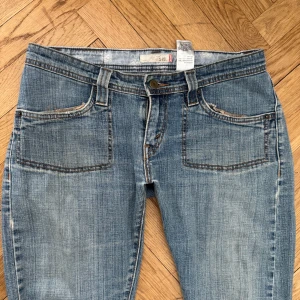 Levis 501 blå jeans - Klassiska blå Levis 501 jeans med raka ben/flare och femficksmodell. Jeansen har normal passform, knappgylf och tydliga Levis-detaljer som röd etikett och läderpatch bak. Perfekta till vardags för en tidlös denimlook.