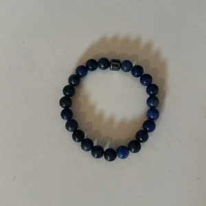 Blått pärlarmband - Snyggt armband med runda blå pärlor och en metallisk detalj. Perfekt accessoar för att ge din outfit lite extra färg.