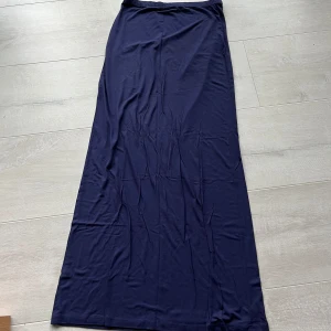 Mörkblå långkjol från Nelly - Säljer en stilren mörkblå långkjol från Nelly. Kjolen har en rak och enkel design i ett mjukt och lätt material, perfekt för en avslappnad och trendig look.