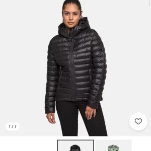 Svart dunjacka med huva från Everest - Säljer en svart dunjacka från Everest med huva och dragkedja. Jackan är lätt, har quiltad design och passar perfekt för kyliga dagar. Snygg och enkel modell som är lätt att matcha med olika outfits. Helt oanvänd, nypris 999kr säljer för 300