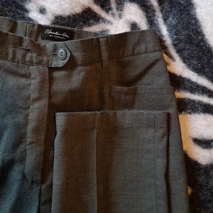 Old fashion - stiliga olivgröna kostymbyxor! - Stiliga olivgröna kostymbyxor med pressveck. Byxorna har knapp(ar) och dragkedja i midjan samt diskreta snyggA fickor fram. (Ena knappen har lossnat, se bild, men den finns och är lätt att sy fast)