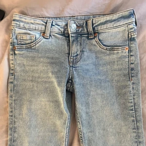 Ljusblå bootcut jeans ultra lowwaist  - Säljer ett par ljusblå bootcut jeans. Byxorna är ultra lowwaist och stängs med knapp och dragkedja. Perfekta till vardags och enkla att matcha med olika toppar.