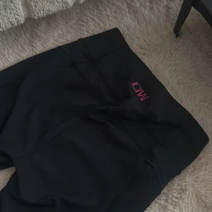 Svarta träningstights från ICANIWILL - Svarta tights från ICANIWILL med diskret logga i rosa vid midjan och reflekterande detaljer på benen. Perfekta för träning med tight passform och dragkedja vid midjan för förvaring. Har klippt bort storleken men tror det är S💗 använda två gånger så jätte fint skick