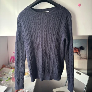 Mörkblå kabelstickad tröja - En mörkblå kabelstickad tröja med rund halsringning och långa ärmar. Tröjan har ett klassiskt flätmönster framtill och ribbade muddar vid ärmslut och nederkant. Pris kan diskuteras och skriv för fler bilder 💓🥰