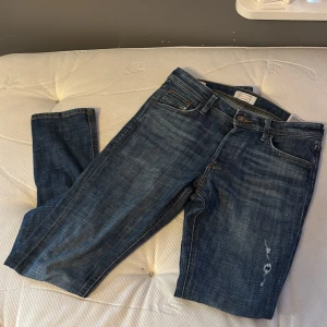 Blå slim fit jeans från Jack & Jones - Säljer ett par blå slim fit jeans från Jack & Jones, modell Glenn. Jeansen har klassisk femficksdesign, orangea sömmar och lätt slitna detaljer framtill. Perfekta för dig som gillar en smalare passform och tidlös denimstil.