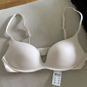 Beige bh från Intimissimi Gioia  - Säljer en oanvänd beige bh från Intimissimi i modellen Gioia med justerbara axelband och vadderade kupor. Perfekt för dig som vill ha en enkel och stilren bh under alla typer av plagg. Säljer då den var för liten❤️