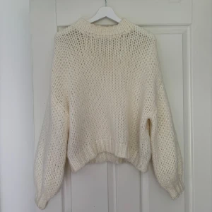 Vit stickad tröja från NA-KD - Säljer en chunky, vit stickad tröja från NA-KD i storlek S/M. Tröjan har oversized passform, breda ärmar och ribbade muddar vid hals, ärmslut och nederkant. Perfekt för lager-på-lager och en mysig look. Passar till sommaren