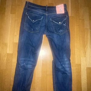 Mörkblå jeansbyxor från Dsquared2 - Säljer ett par mörkblå jeans från Dsquared2 med klassiska fem fickor och slitna detaljer. Byxorna har raka ben och normal passform. Perfekta för dig som gillar en tidlös denimlook.