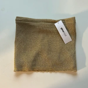 Guldig glittrig tubtopp från Gina Tricot - Säljer en snygg guld glittrig tubtopp från Gina Tricot. Toppen är ofshoulder och har en tight passform. Aldrig använd och har lappen kvar. Perfekt till fest😽❤️❤️