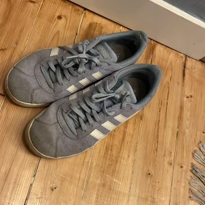 Ljusblå Adidas sneakers med vita ränder - Säljer ett par klassiska ljusblå Adidas sneakers med vita ränder på sidorna. Skorna har snörning och är tillverkade i mocka med en platt sula. Perfekta för en avslappnad stil och passar till det mesta. De är lite smutsiga men säkrer något man kan fixa till lätt. De är i storlek 39 1/3 men passar vanlig 39. 