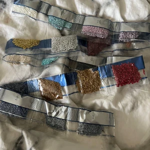 Färgade pärlor för diamond painting - Olika små plastpärlor i flera färger som används till diamond painting. Pärlorna är sorterade i små plastpåsar och finns i nyanser som vitt, blått, rosa, rött, gult och beige. Perfekt för att skapa detaljerade och färgglada motiv.
