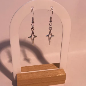 Silvriga stjärnformade örhängen - Säljer ett par coola silvriga örhängen i form av stjärnor. De har en öppen, spetsig design och hängs på krok. Perfekta för att ge din look lite edge och glans! Super trendiga!