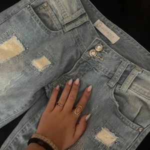 Ljusblå Lågmidjade jeans - Säljer ett par ljusblå jeans från Goodies med snygga och unika detaljer. Jeansen har sytts om från skinny till bootcut!💕Dubbla knappar i midjan och klassiska fickor både fram och bak. Perfekta för en trendig look💗Det står strl 38 men skulle säga att de mer är som en 36 eftersom då de är aningen små i låren. (OBS! Har ingen bild på pga att de inte passar)