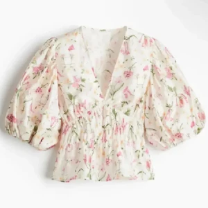 Blommig puffärm blus från H&M - Supersöt blommig blus med puffiga trekvartsärmar och v-ringning. Ljus botten med rosa, gröna och gula blommor. Smockad midja ger en snygg siluett och toppen är lätt och luftig i bomull. Perfekt för vår och sommar, matcha med jeans eller kjol för en fräsch look. Den är m men passar mig som har S