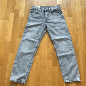 Grå relaxed jeans från H&M, 30/32 - Snygga grå jeans från H&M i relaxed fit med raka ben och klassisk femficksdesign. Jeansen har knäppning med knappar och är tillverkade i mjukt bomullsmaterial. Perfekt för dig som gillar en loose och chill stil.