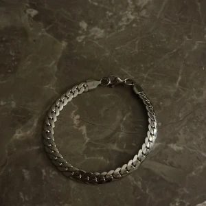 Kedjearmband i silver - Snyggt och stilrent armband med breda, platta länkar i silverf. Perfekt för dig som gillar minimalistisk och modern stil. Låset är klassiskt och enkelt att använda. Passar både till jeans och hoodie eller till en mer dressad look.