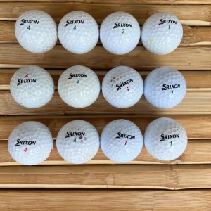 Srixon mix (12 pack) - Bilderna visar ett set med begagnade Srixon golfbollar, perfekta för dig som vill komma igång med golf eller fylla på din samling. Bollarna har olika nummer och är i varierande skick, redo för nya rundor på banan. Ett smart val för unga golfare som vill spela mer till ett bra pris. Pris kan diskuteras 