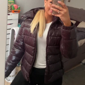 Svart pufferjacka med huva - Säljer en snygg svart pufferjacka från lager 157 med huva och breda, quiltade sektioner. Jackan har dragkedja framtill och är långärmad, perfekt för kalla dagar. 